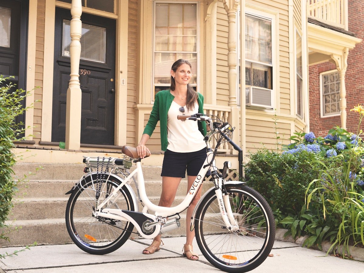 Smiling woman standing behind her bike.